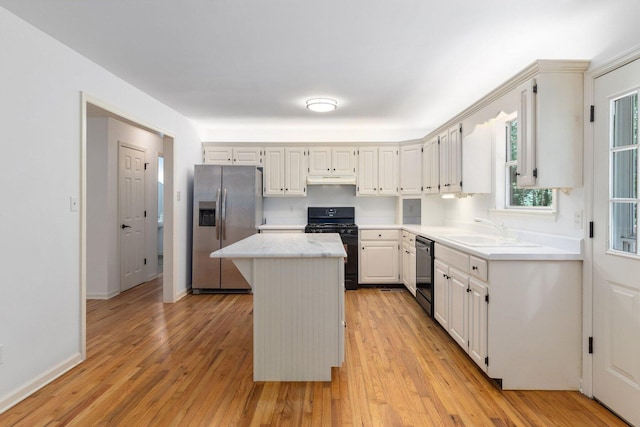 1623 Devlan Forest Ln, Signal Mountain, TN 37377 - kitchen with black appliances, light countertops, a kitchen island, light wood finished floors, and under cabinet range hood