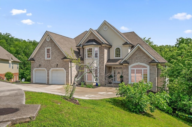 view of front of property featuring an attached garage, concrete driveway, a front yard, brick siding, and roof with shingles