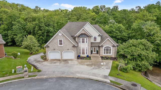 traditional home with driveway, a front yard, a garage, and brick siding