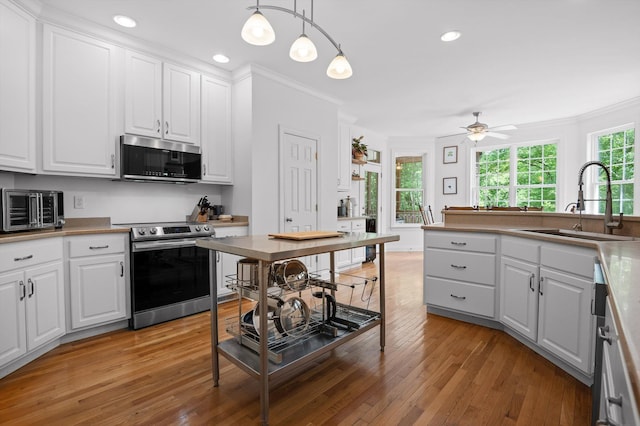 kitchen with appliances with stainless steel finishes, a sink, white cabinetry, crown molding, and recessed lighting