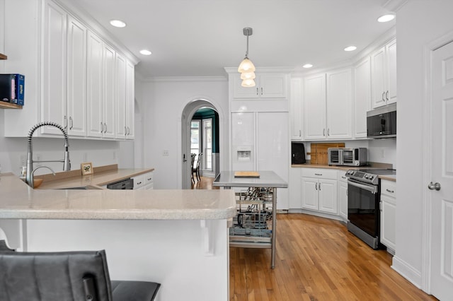 kitchen featuring appliances with stainless steel finishes, arched walkways, a peninsula, white cabinetry, and a sink