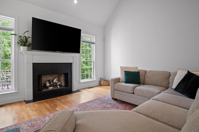living room featuring vaulted ceiling, wood finished floors, a fireplace with flush hearth, recessed lighting, and baseboards