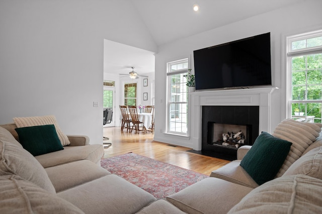 living room featuring a fireplace with flush hearth, light wood-type flooring, high vaulted ceiling, recessed lighting, and a ceiling fan