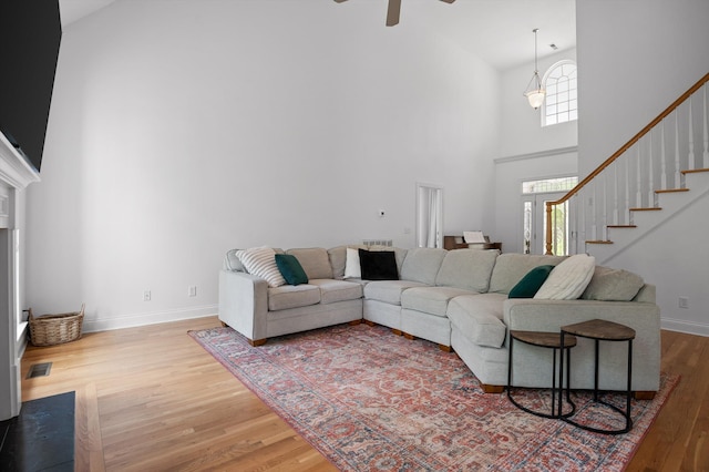 living room with high vaulted ceiling, wood finished floors, a ceiling fan, stairway, and baseboards