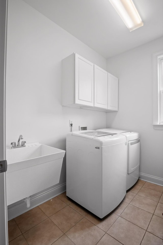 laundry area featuring cabinet space, washing machine and clothes dryer, light tile patterned floors, and baseboards