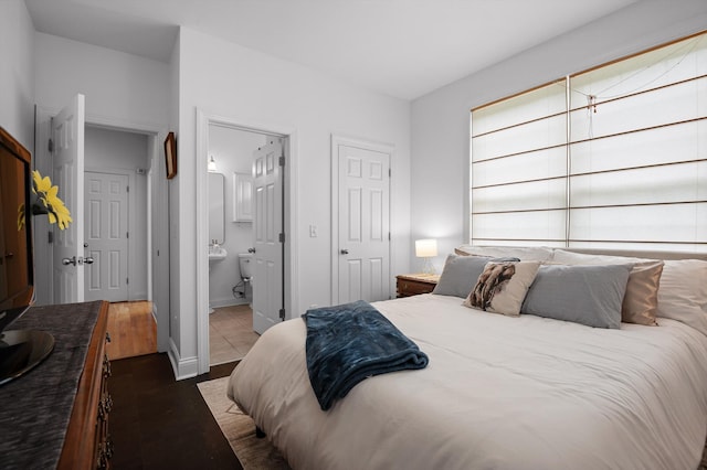 bedroom featuring ensuite bath and baseboards