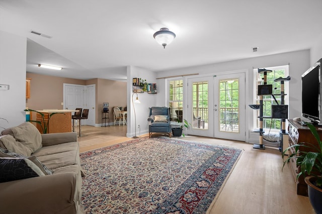 living room with healthy amount of natural light, french doors, and light wood-type flooring