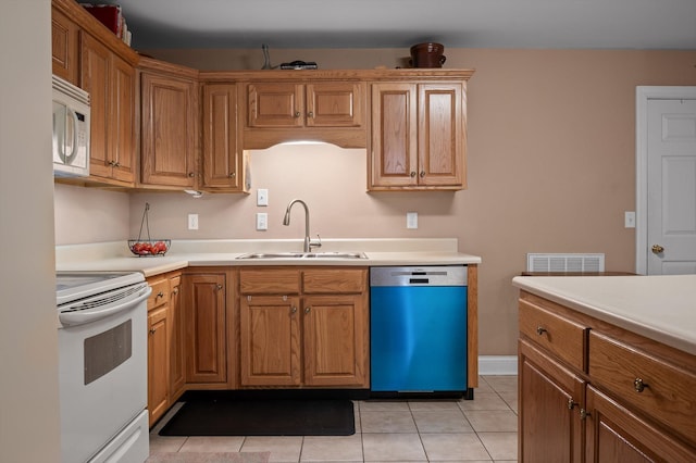 kitchen featuring white appliances, a sink, light tile patterned floors, light countertops, and brown cabinetry