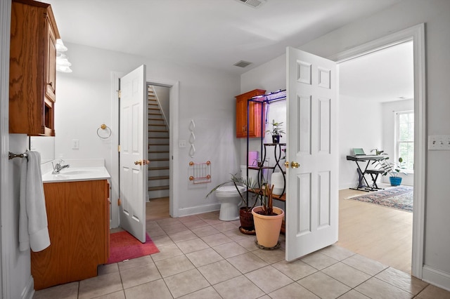 bathroom featuring toilet, tile patterned flooring, vanity, and baseboards