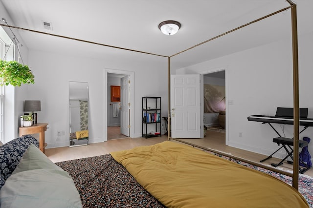 bedroom featuring wood finished floors, baseboards, and connected bathroom