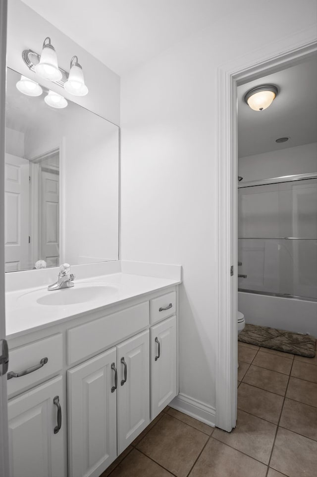 bathroom featuring tile patterned floors, toilet, vanity, and shower / bath combination with glass door