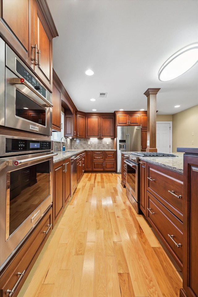 7470 Twin Brook Dr, Chattanooga, TN 37421 - kitchen featuring high end appliances, light wood-style floors, light stone countertops, decorative columns, and decorative backsplash