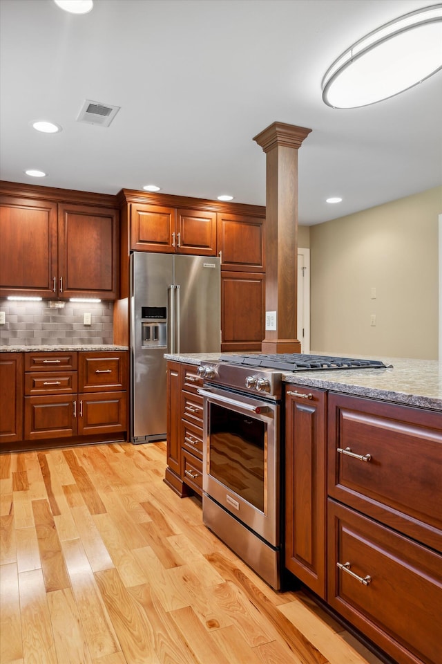 7470 Twin Brook Dr, Chattanooga, TN 37421 - kitchen featuring premium appliances, light stone counters, light wood-type flooring, backsplash, and ornate columns