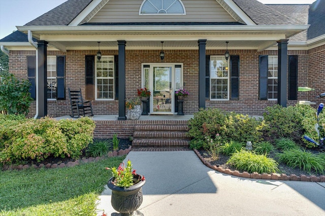property entrance with brick siding, a porch, and a shingled roof