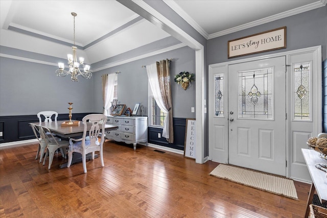 dining area featuring a chandelier, crown molding, wood-type flooring, and a wainscoted wall