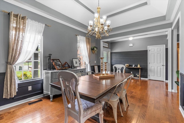 dining area featuring a chandelier, wood-type flooring, baseboards, and crown molding