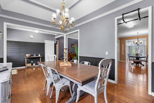 dining area featuring a chandelier, hardwood / wood-style floors, crown molding, and wainscoting