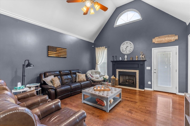living area with a ceiling fan, a fireplace, wood finished floors, and high vaulted ceiling