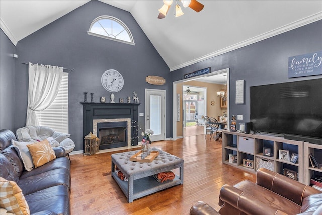 living room featuring ceiling fan, crown molding, wood finished floors, a fireplace with flush hearth, and high vaulted ceiling
