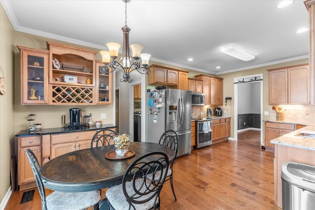 dining space with a chandelier, light wood-style floors, ornamental molding, recessed lighting, and washer / dryer