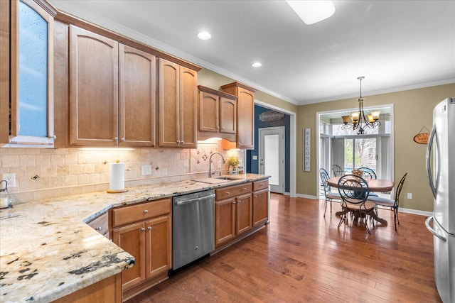 kitchen with appliances with stainless steel finishes, a sink, tasteful backsplash, a chandelier, and ornamental molding