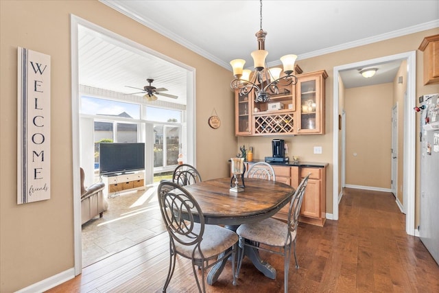dining area featuring crown molding, wood finished floors, baseboards, a chandelier, and ceiling fan