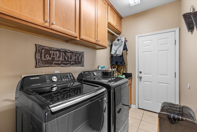 clothes washing area with cabinet space, washer and dryer, and light tile patterned floors