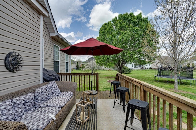 deck featuring a trampoline and a lawn