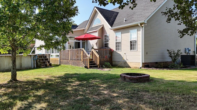 rear view of house featuring a fire pit, a wooden deck, a shingled roof, and a yard
