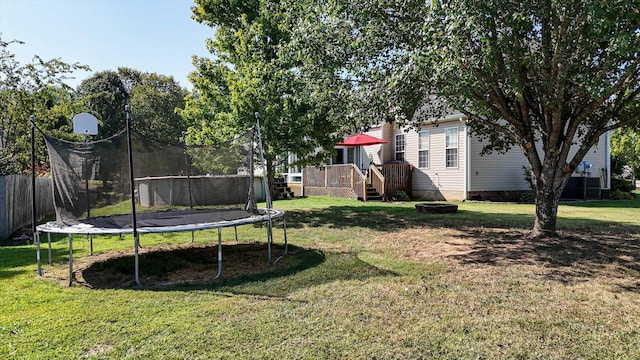 view of yard with a trampoline and a deck