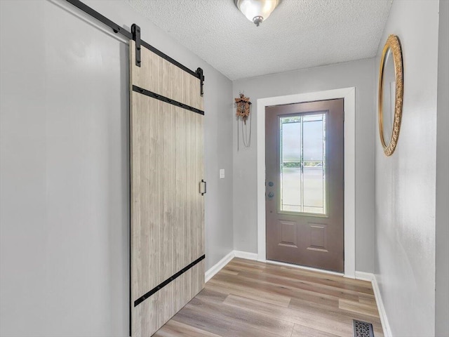 123 Paddle Wheel Ct, Cohutta, GA 30710 - doorway featuring a barn door, light wood-type flooring, baseboards, and a textured ceiling