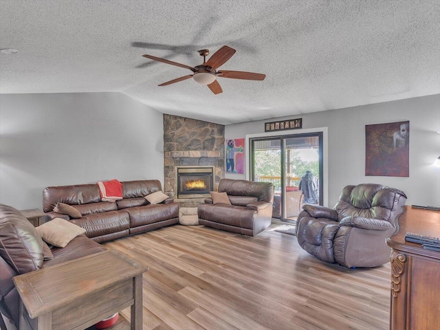 123 Paddle Wheel Ct, Cohutta, GA 30710 - living room featuring light wood-style floors, a ceiling fan, a textured ceiling, a stone fireplace, and vaulted ceiling