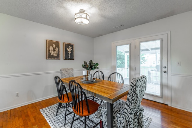 dining space with a textured ceiling, wood finished floors, and baseboards