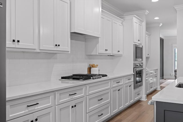 kitchen featuring ornamental molding, recessed lighting, light wood-type flooring, white cabinetry, and decorative backsplash