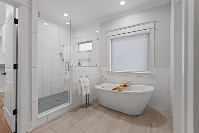 bathroom featuring a freestanding tub, a stall shower, ornamental molding, recessed lighting, and tile walls