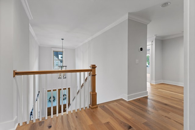 stairway with ornamental molding, healthy amount of natural light, wood finished floors, and baseboards