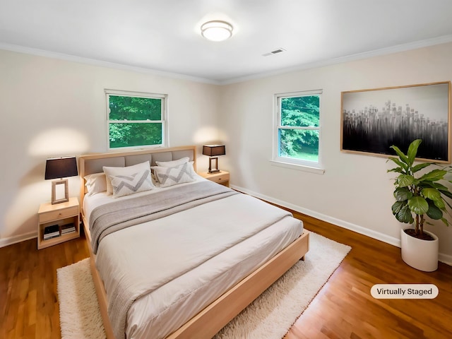 bedroom with crown molding, wood finished floors, and baseboards