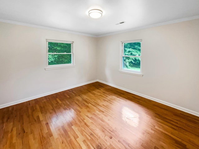 unfurnished room with ornamental molding, wood finished floors, and baseboards