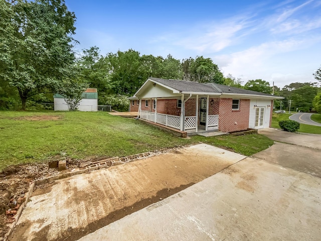 view of front of home featuring brick siding, a front lawn, french doors, and covered porch