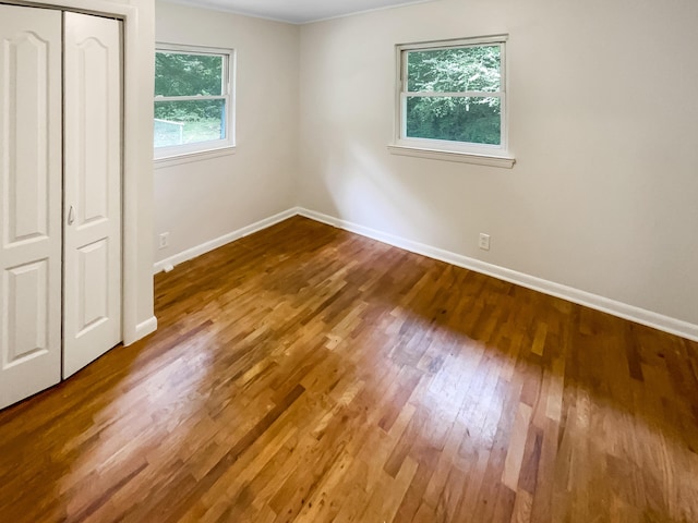 unfurnished bedroom featuring wood finished floors, baseboards, and a closet