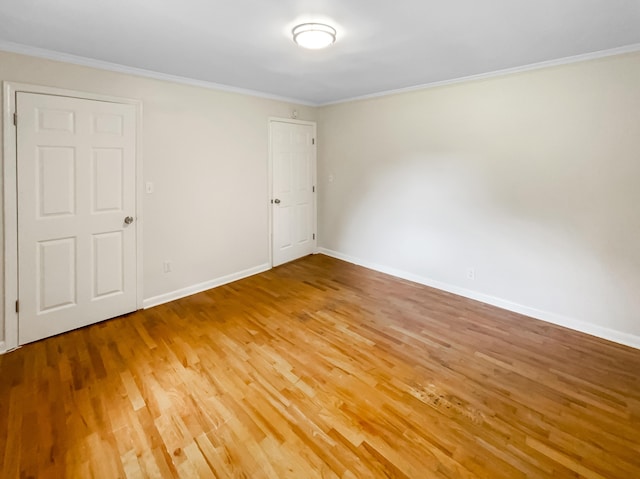 spare room featuring light wood-style floors, baseboards, and ornamental molding