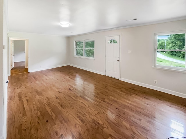 unfurnished living room with crown molding, wood finished floors, and baseboards