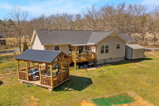 back of property with a shingled roof, a deck, a yard, and a gazebo