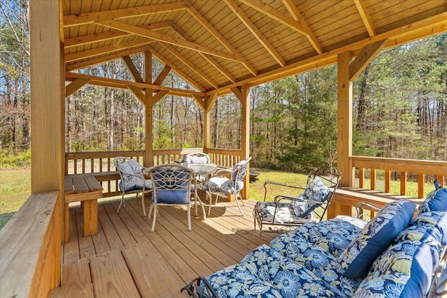 deck with an outdoor hangout area, outdoor dining area, a gazebo, and a wooded view