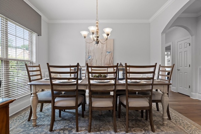 dining area featuring wood finished floors, arched walkways, ornamental molding, and a chandelier