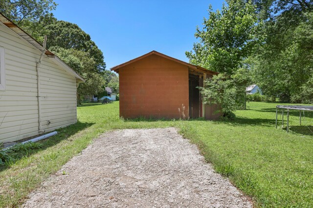506 Daugherty St, Lafayette, GA 30728 - view of side of home with a trampoline, a lawn, an outdoor structure, and concrete block siding