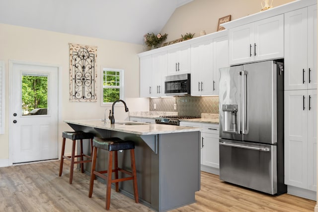 5834 Caney Ridge Cir, Ooltewah, TN 37363 - kitchen with stainless steel appliances, a sink, vaulted ceiling, backsplash, and a kitchen island with sink