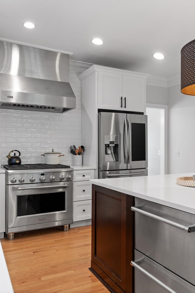 715 Forest Ave, Chattanooga, TN 37405 - kitchen featuring appliances with stainless steel finishes, wall chimney exhaust hood, light countertops, white cabinetry, and ornamental molding