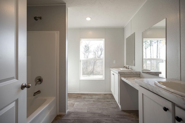full bathroom with double vanity, crown molding, shower / bath combination, wood finished floors, and a textured ceiling