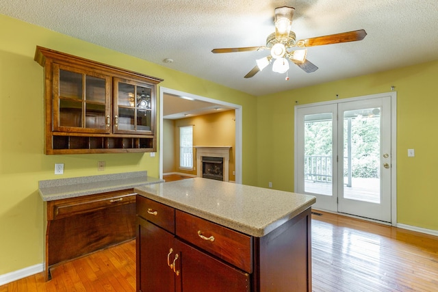 13709 Stormer Rd, Soddy Daisy, TN 37379 - kitchen with light countertops, light wood finished floors, a ceiling fan, glass insert cabinets, and a textured ceiling